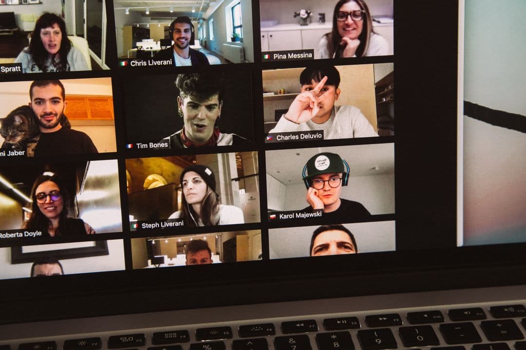 Zoom call with 9 participants, including men and women, in various settings such as offices, homes, cafes, and a bakery.